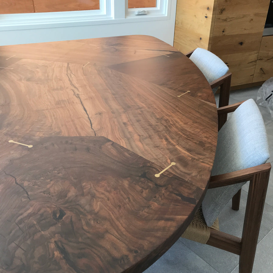 Patchwork walnut dining table with brass barbell inlaid joinery