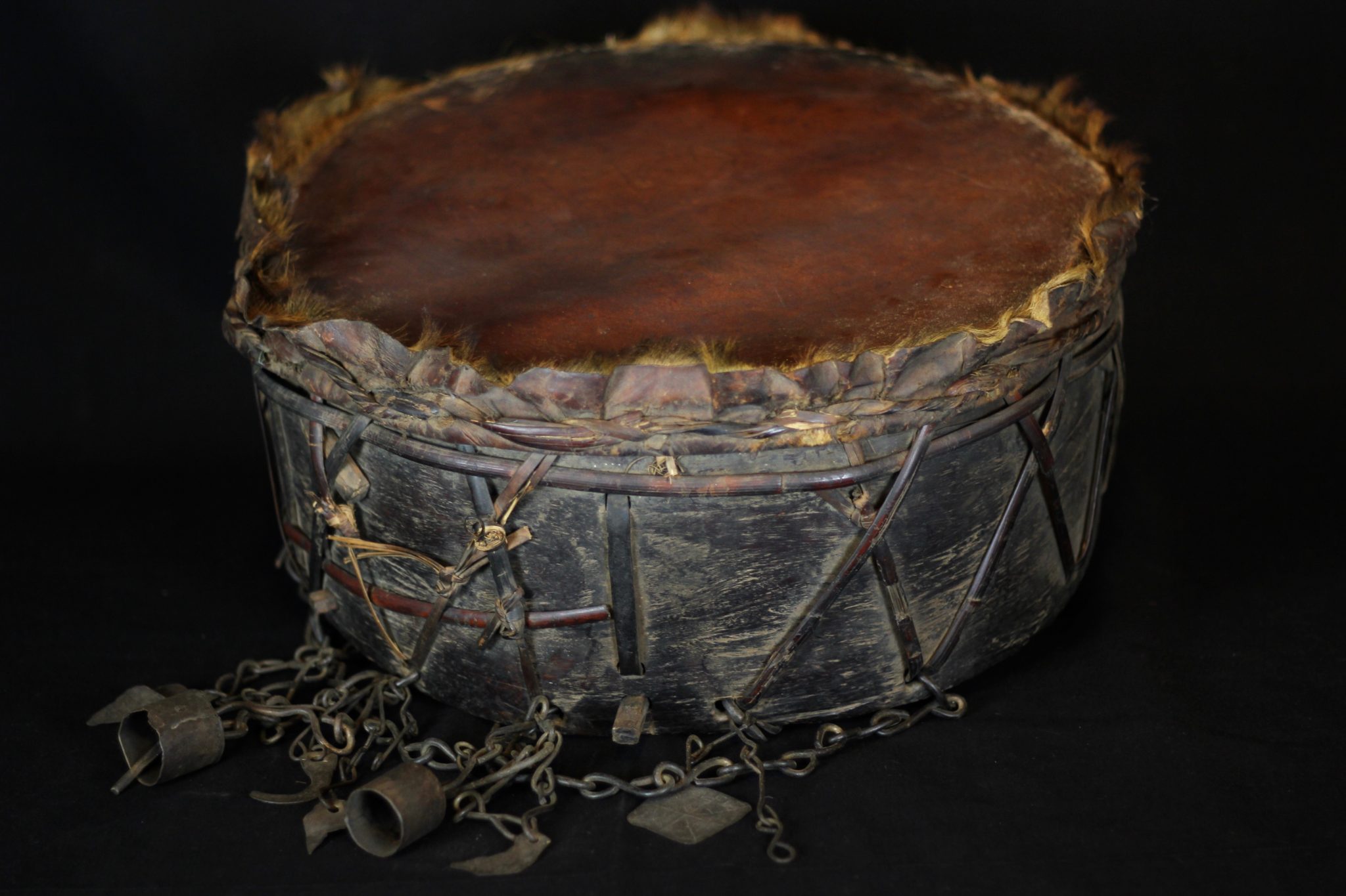 Sacred Ritual Drum, Nepal, Mid to late 19th c., Skin stretched over wood, iron, shaman bells and amulets, To facilitate entering and maintaining a trance state necessary for the shaman to perform rituals 17 ½” x 8” x 8” (plus 7” bell chains), $1400.