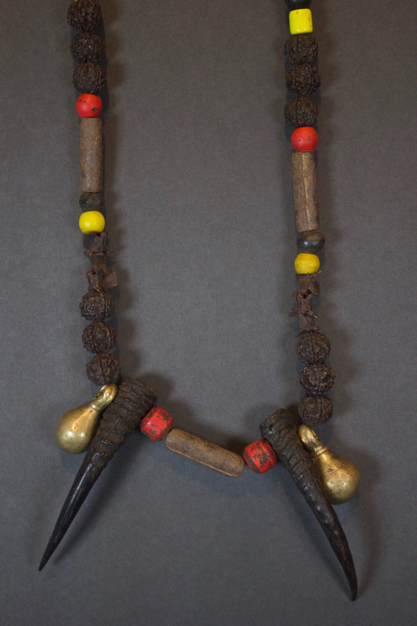 Naga Mala Shaman Necklace Nepal Late 19th c. Snake bone, rudraksha seeds, Himalayan goat horn, old European handmade glass trade beads, Brass crotal bells The Naga Mala are primarily used in healing ceremonies for protection and to connect the shaman with the sacred snake gods and goddesses who help inform their work. The preparation of the snake bones and necklace has an intricate sacred ritual to properly empower them. The Rudraksha (enlightened) seeds symbolize divine wisdom and are traditionally used as prayer beads. The bells make a sound that evoke ancestor spirits and helps the shaman transition into a trance state for ceremonies. 22” x 7” x 1 ¾” $750