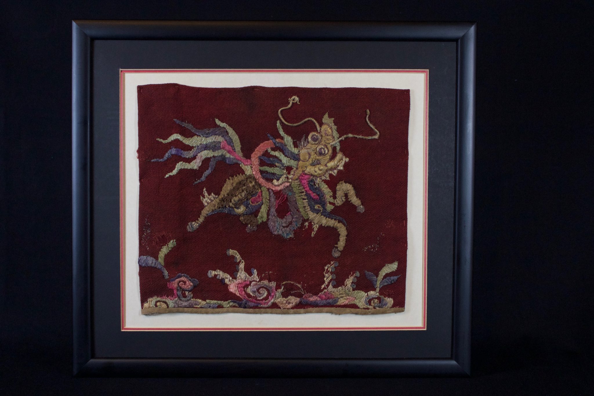 Sacred Unicorn (Kỳ lân) Panel (rare), Vietnam, Bac Ninh province, Mid 19th c, Red cotton textile with hand embroidered silk and precious-metal-wrapped thread. One of the four sacred animals, the unicorn symbolizes purity, happiness and wealth. If the unicorn appears, many good things will happen. It is often hung over the altar table in pagodas, temples or in homes of traditional families. Its strength and faithful nature are desirable for guarding temples and places of worship. Almost all of these pieces from this time period are portrayed in blue, cream and metallic color schemes. Because of its coloring, this panel is unusual and particularly desirable. 15 ½” x 17 ½” x ¾”, $590.