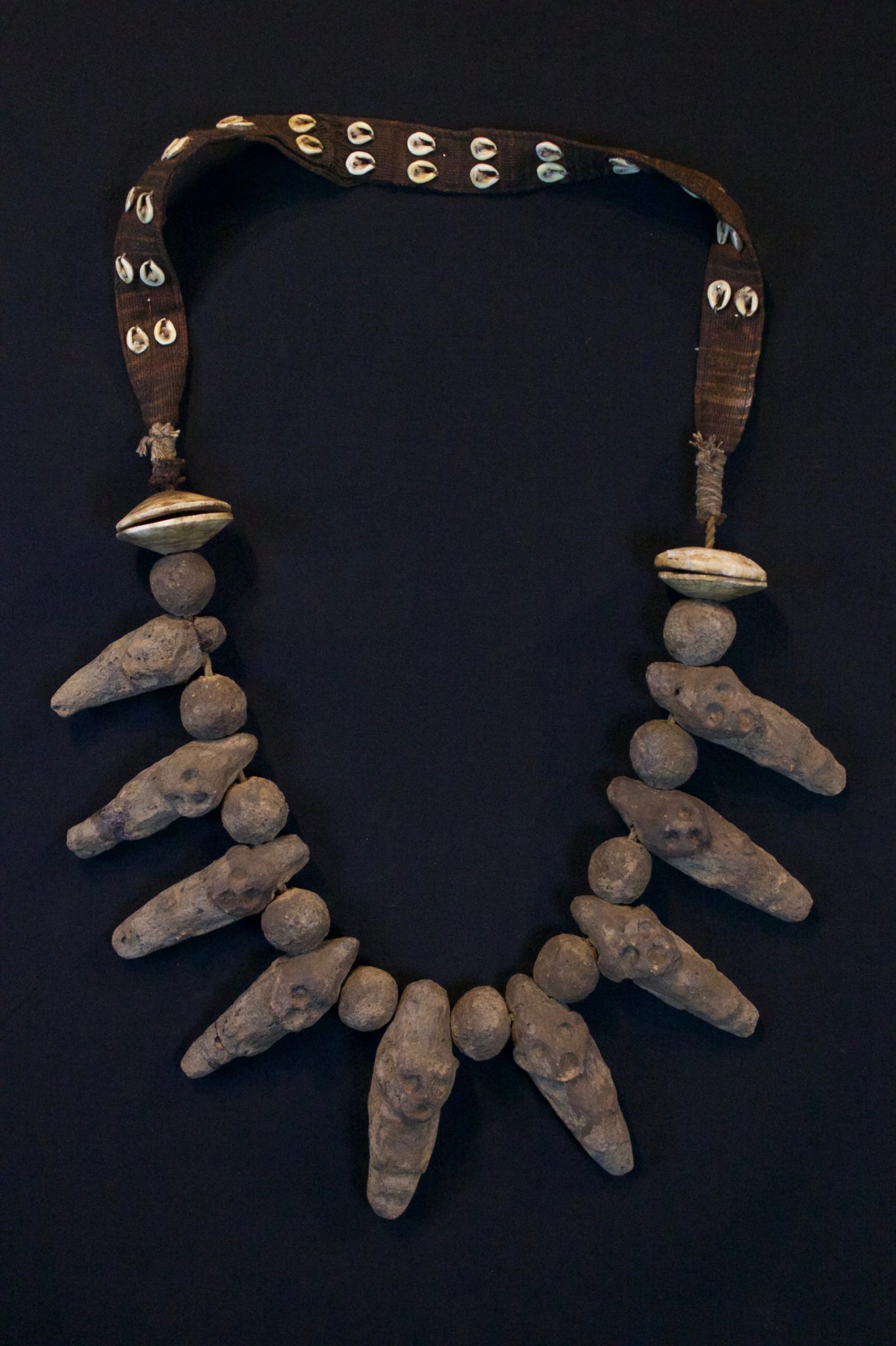 Shaman Amulet Necklace, Timor Island, Lesser Sunda Islands, Indonesia, Early 20th c, Ceramic stone figures and beads, shell, cotton. Worn by the shaman for healing ceremonies. 20 ½” x 11” x 1 ¾”, $650.