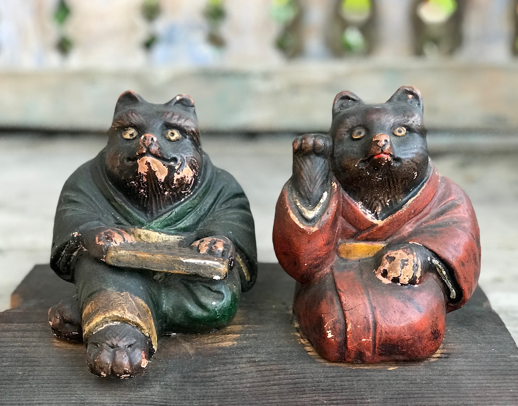 2 Wooden Tanuki in kimonos with abacus, and calling for good luck, Tanuki have a very complex and interesting folkloric history. While largely unheard of in the states, Tanuki have been among the most significant characters in Japan since ancient times. Contemporary Tanuki are primarily a welcoming symbol of prosperity. In the mid 20th century the character was adapted, both visually and symbolically, to suit modern culture and, although they retain much of their prankster persona from the original 16th century creatures, they are much more benign. They have a long list of supernatural powers, most notable shape-shifting. Ancient Tanuki, humorously portrayed in block prints are now mostly found in museums and private collections. Tanuki statues are often found in restaurant or shop windows and outside temples. Famous for getting drunk and not paying their bills, they are usually portrayed wearing a straw hat and carrying a flask of sake and a ledger of promissory notes. Thus they can also serve as cautionary figures against the hazards of overindulging in alcohol. They always have big bellies and humorously large testicles which they use as drums. 5" x 10 1/4" x 7 1/2", sold., thedavidalancollection.com , solana beach, ca